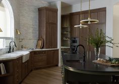 A spacious and stunning kitchen space with curved green tone island and beautiful wood cabinetry.