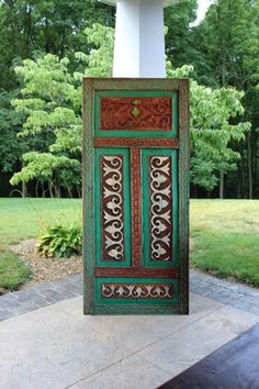 an old door is painted green and brown with designs on the outside, along with brick walkway