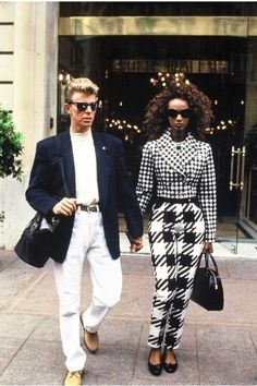 a man and woman walking down the street with a paper mask on their head in front of them