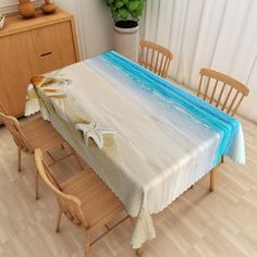 a dining room table covered with a blue and white tablecloth next to wooden chairs