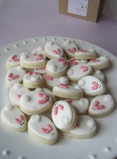 a white plate topped with lots of cookies covered in frosting bunny face cut outs