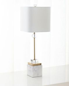 a white table with a lamp on it and a window in the backround