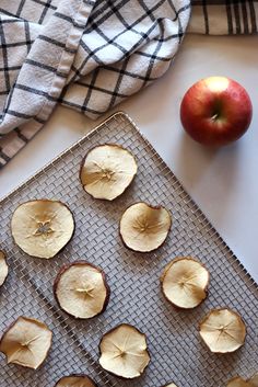 an apple is sitting on a cooling rack next to some sliced apples and a towel