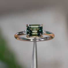 This low profile, three stone setting offers a subtle hint of sparkle with two, 1.7mm natural white diamonds set into the shoulders. Crafted from recycled gold or platinum, it features a smooth, polished finish or a rustic matte texture. Ideal for pairing with curved bands, this ring will stack well. Emerald White Gold Ring, Green Sapphire Ring Engagement, Green Diamond Ring, Low Profile Engagement Rings, Emerald Cut Sapphire Ring, Antique Emerald Ring, Green Diamond Rings, White Gold Sapphire Ring, Sunstone Jewelry