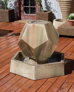 a concrete water fountain sitting on top of a wooden deck