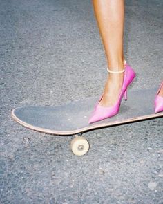 a woman's feet in high heels on top of a skateboard