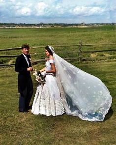 a bride and groom standing in front of a fence