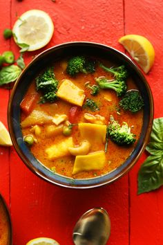 a bowl of soup with broccoli, cheese and lemons on the side