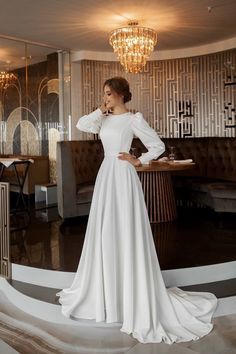 a woman in a white wedding dress posing for the camera with her hands on her hips