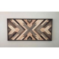 a wooden wall hanging on the side of a wall with an arrow pattern in it