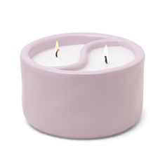 two white candles sitting in a pink container