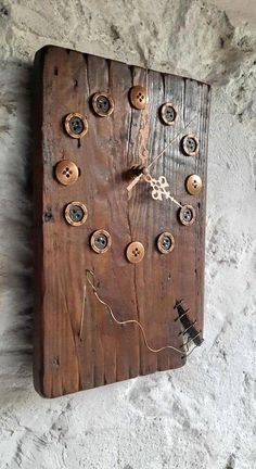 a clock made out of wood with buttons and chains on the face is hanging on a wall