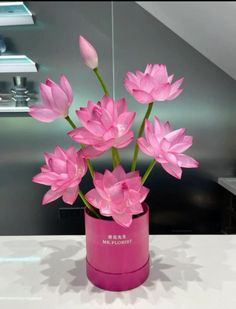 a pink vase with flowers in it on a table