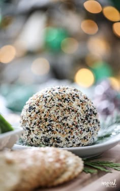 a white plate topped with a sesame seed ball next to crackers and asparagus