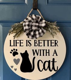 a wooden sign that says life is better with a cat on it and a bow hanging from the front door