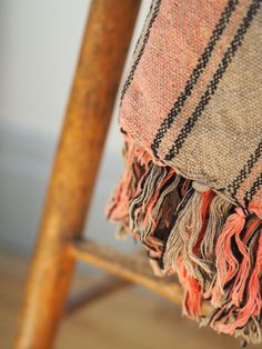 an old wooden chair with a plaid blanket on it's back and seat cushion