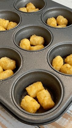 a muffin tin filled with tater tots on top of a wooden table