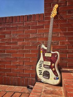 an electric guitar sitting on top of a brick wall