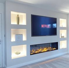 a television mounted on the wall in a living room with built - in shelves and a fire place