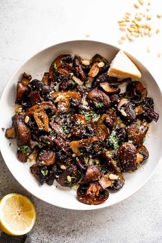 a white bowl filled with cooked mushrooms and garnished with parmesan cheese