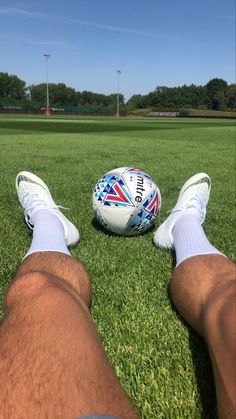 a person laying on the grass with their feet near a soccer ball in front of them