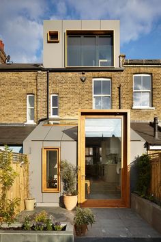 a house that has some plants in front of it and the door is open to let in lots of light