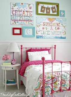 a bedroom with pink bedding and pictures on the wall