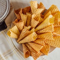 several waffle cones on a plate next to an air fryer and a towel