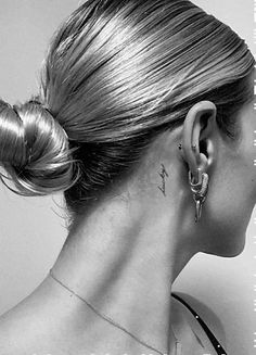 a woman with a tattoo on her neck and behind her ear