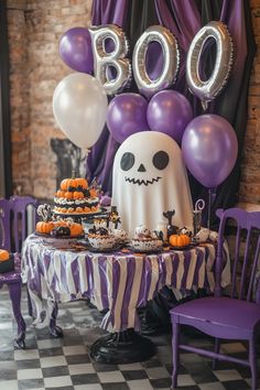 a table topped with cake and balloons next to a halloween themed chair cover filled with cupcakes