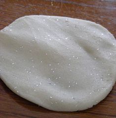 an uncooked pizza dough sitting on top of a wooden table