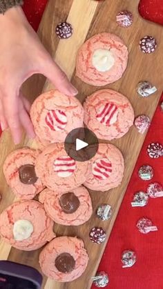 someone is decorating some cookies on a wooden board with chocolates and candy canes