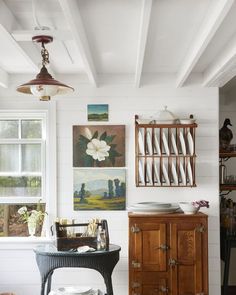 a room with white walls and wooden furniture in front of a window that has pictures on the wall