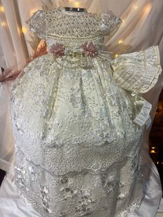 a white dress on display in front of a window with curtains and lights behind it