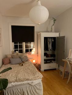 a small bedroom with a bed, dresser and lamp in it's corner next to a window