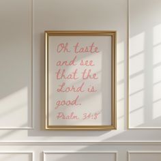 a white wall with a gold frame on it and a pink quote above the fireplace