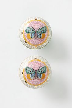 two small round dishes with butterfly designs on them