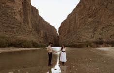 two people standing in the middle of a river