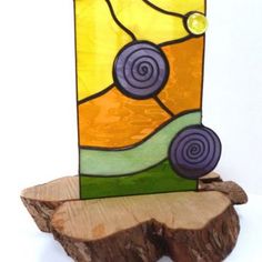 a piece of wood sitting next to a stained glass vase on top of a tree stump