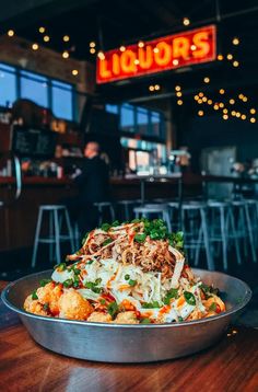 a bowl of food sitting on top of a wooden table in front of a bar