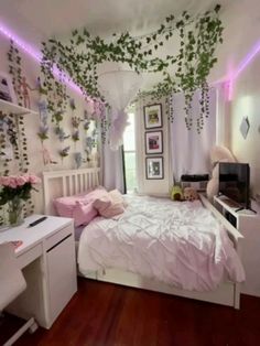 a bedroom decorated in pink and white with plants hanging from the ceiling