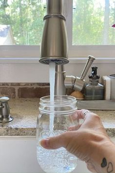 a person's hand is under a faucet that has water in it