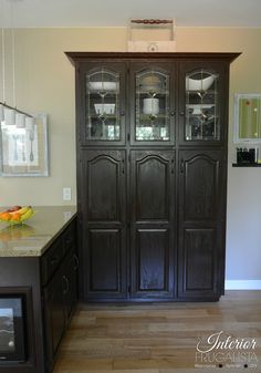 a large wooden cabinet with glass doors in a living room next to a dining room table