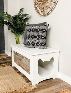 a white bench sitting next to a plant on top of a wooden floor