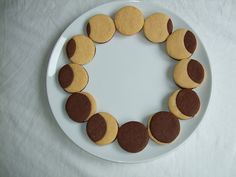 a white plate topped with lots of cookies on top of a tablecloth covered table