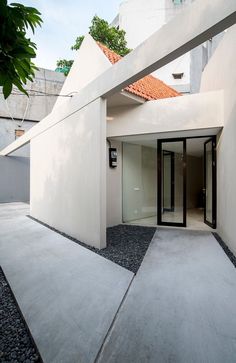 an entrance to a house with white walls and black doors on the outside, surrounded by gravel