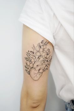 a woman's arm with flowers and a heart tattoo on the left side of her arm