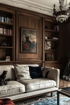 a cat sitting on top of a couch in a living room next to bookshelves