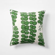 a green and white pillow with leaves printed on it's side, against a white background