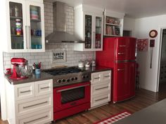 a red stove top oven sitting inside of a kitchen next to a refrigerator freezer